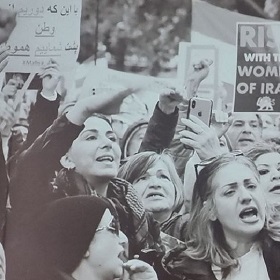 Black and white photo of a group of people hold posters protesting about the human rights abuse in Iran